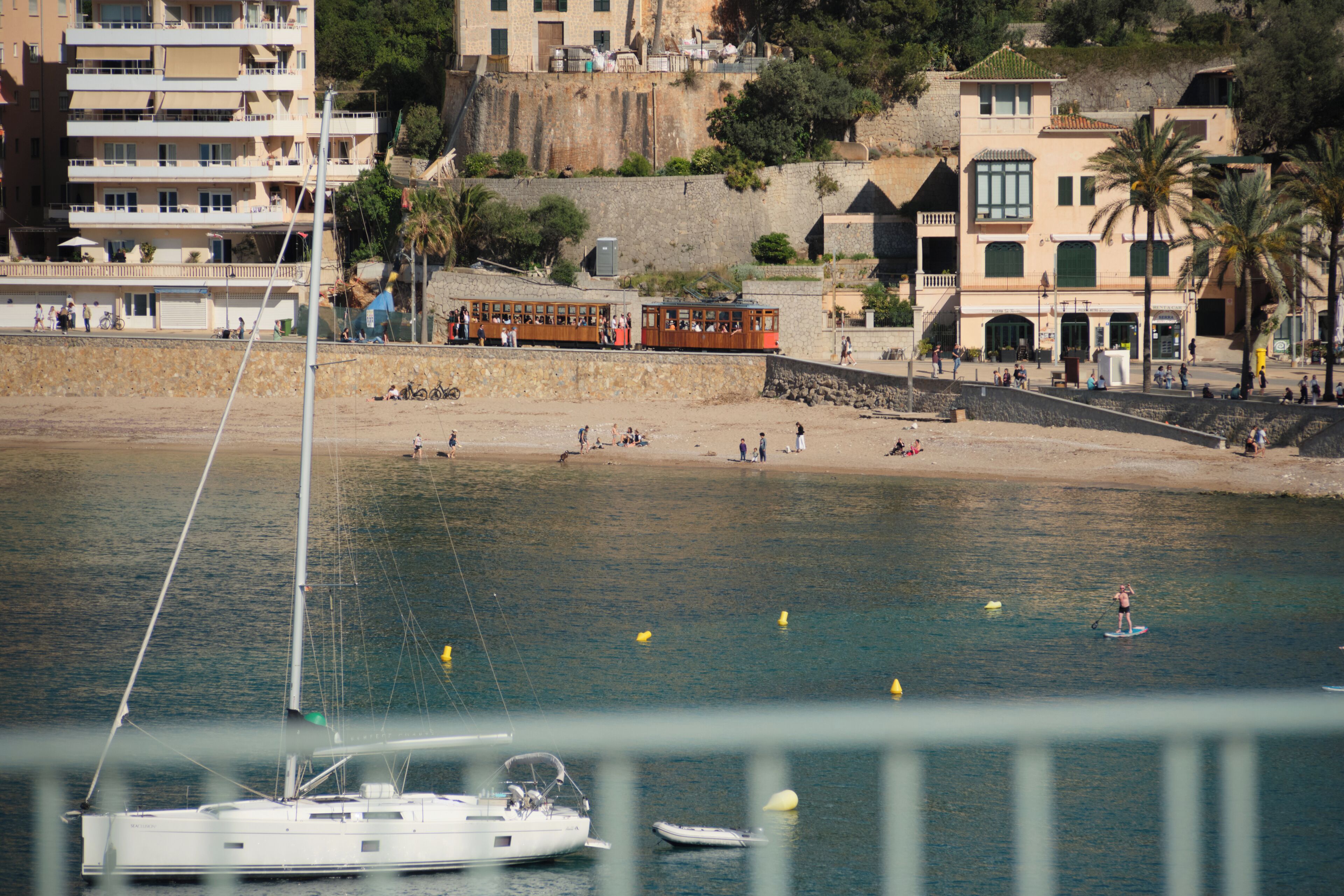 Un pueblo costero con una playa de arena, una hilera de edificios y un ferry en el agua.