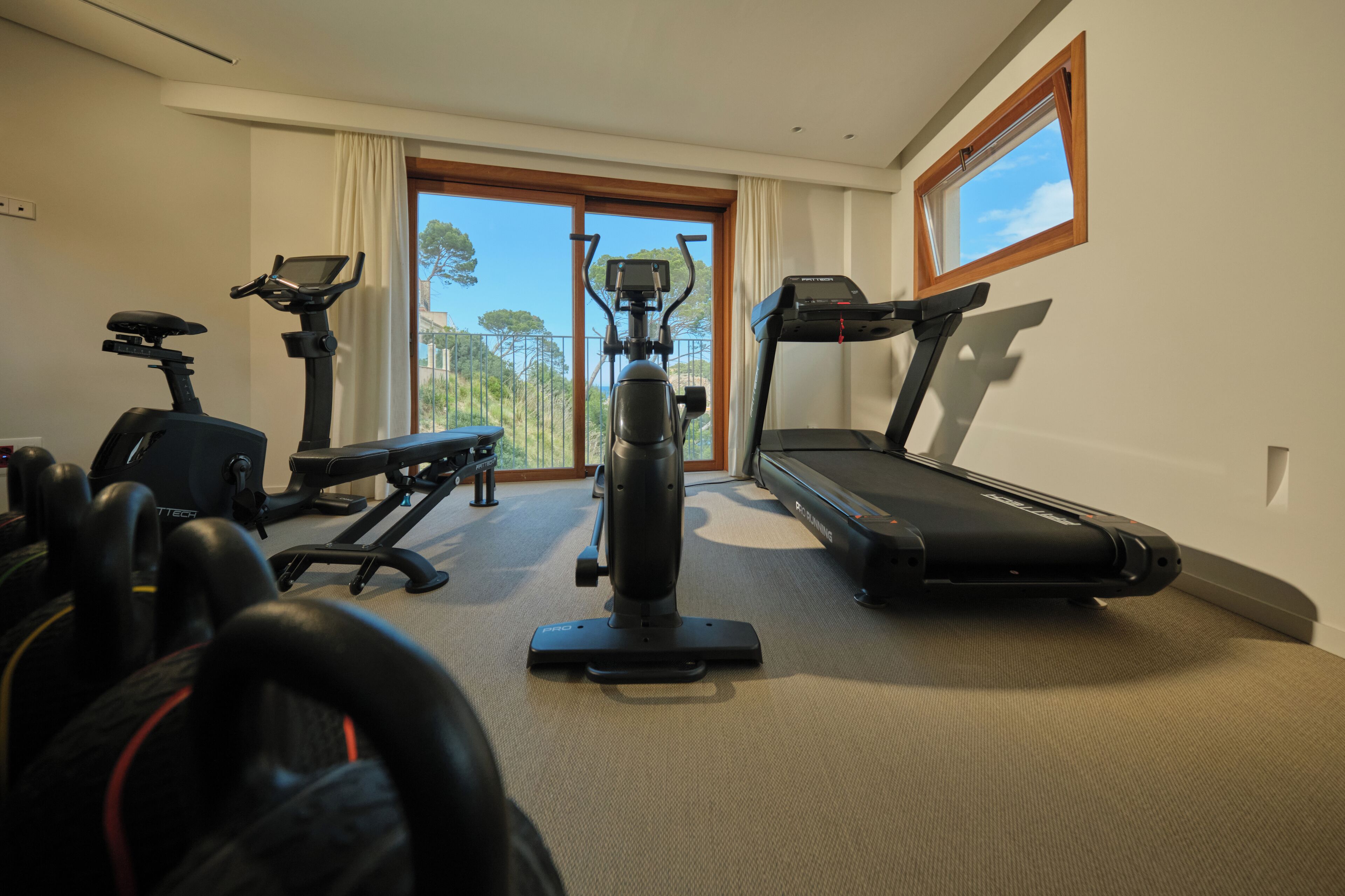 A home gym with a treadmill, elliptical, and stationary bike.
