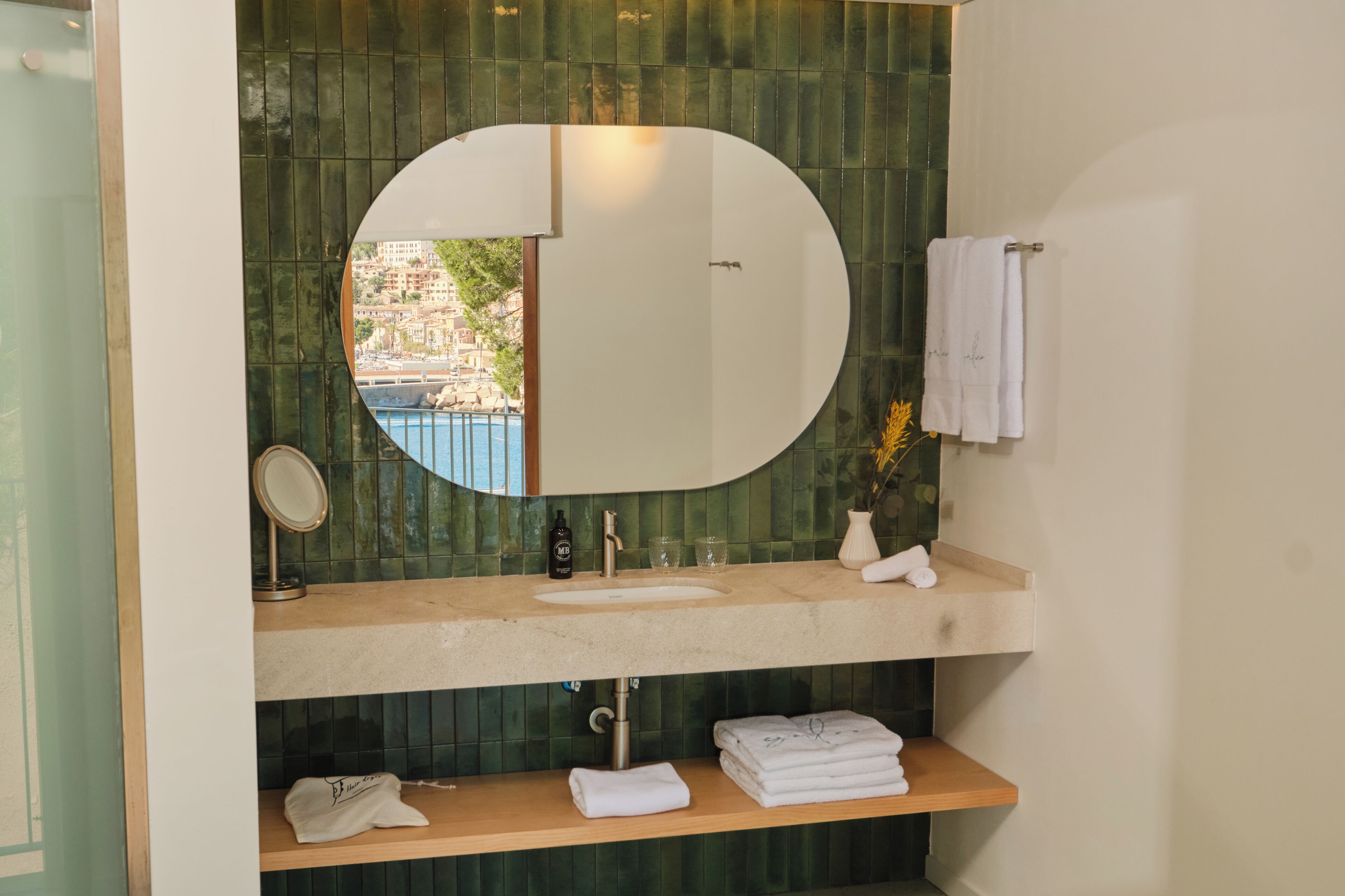 Un baño con un espejo redondo, un lavabo y un perchero para toallas.