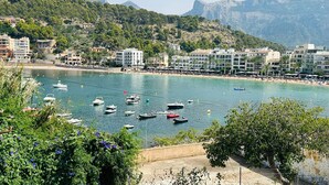 A coastal town with buildings along the beach, boats in the water, and a mountainous backdrop. - Hotel Salino Port Soller - Adults Only +16 (Sóller)
