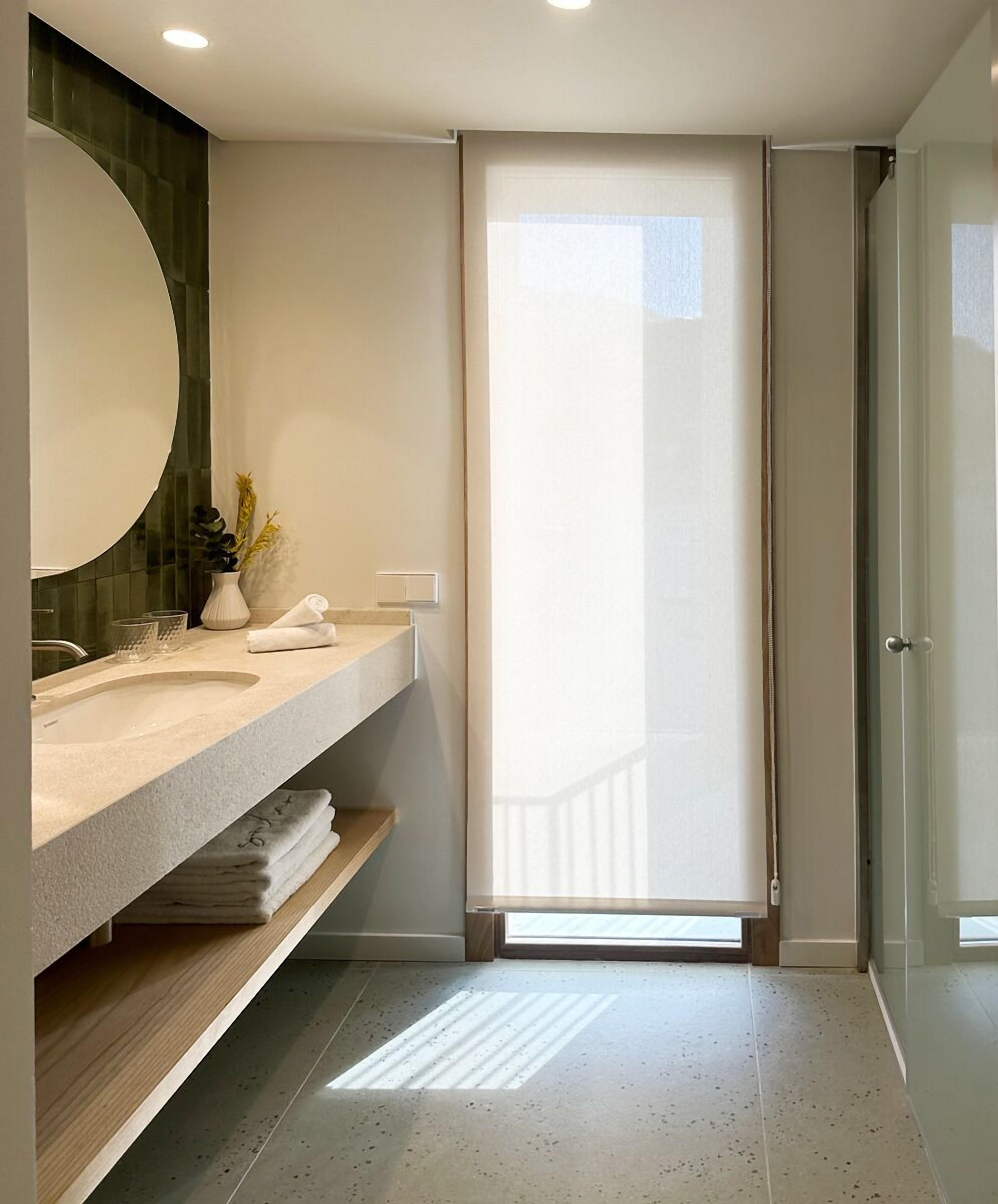 A modern bathroom with a large mirror, a sink, and a shower area.