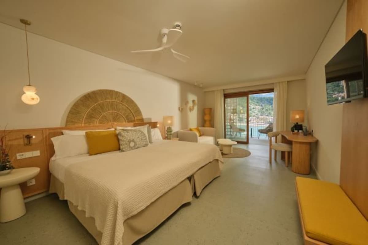 A hotel room with a bed, bedside tables, a desk, a chair, and a TV.