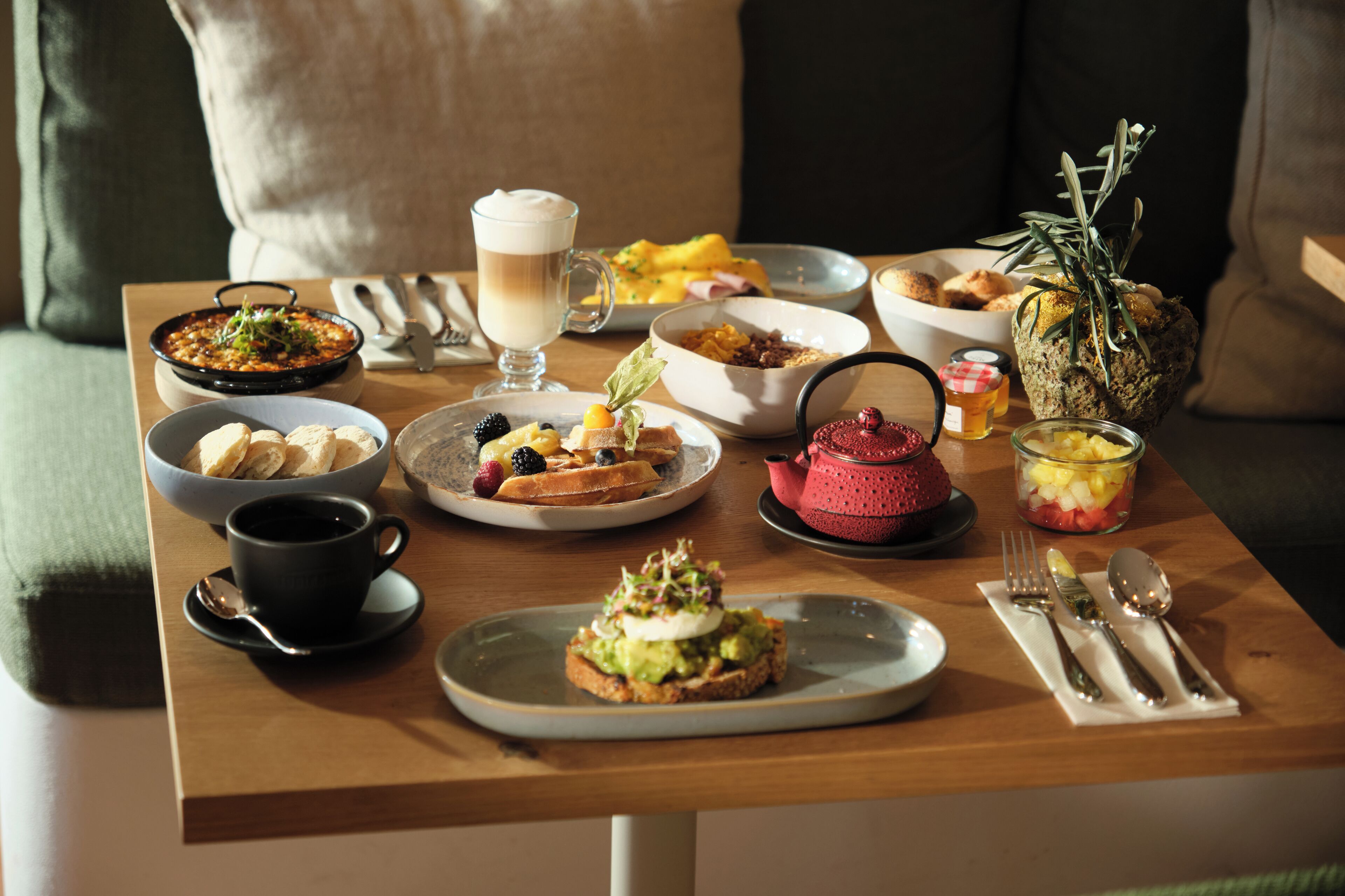 A breakfast table with various dishes, including pancakes, a bowl of fruit, and a cup of coffee.