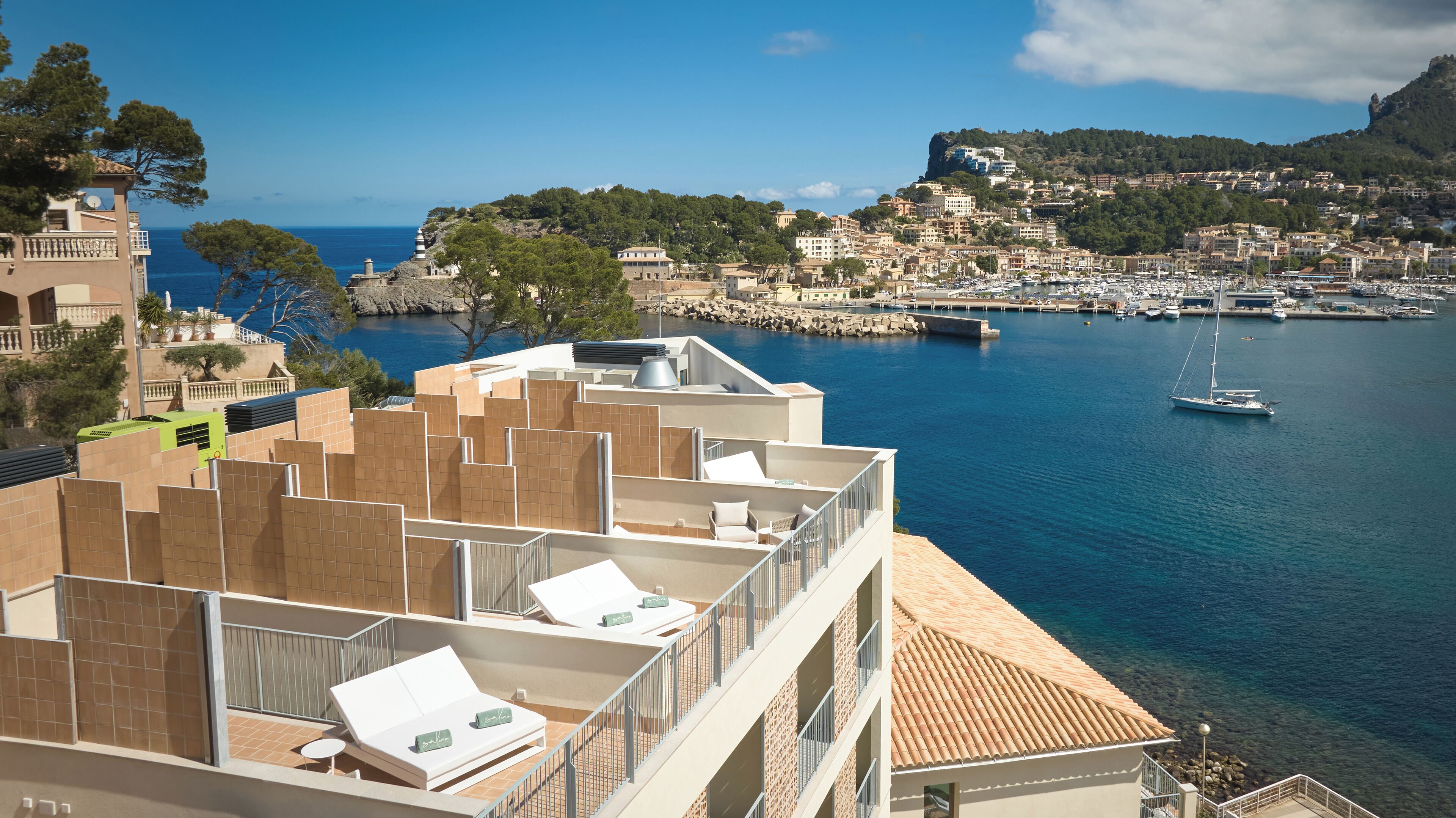 Un hotel frente al mar con varios balcones con vistas a un puerto deportivo y una ciudad.