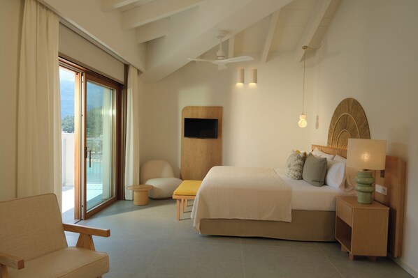 Een moderne slaapkamer met een bed, een stoel, een klein tafeltje en een aan de muur bevestigde televisie.