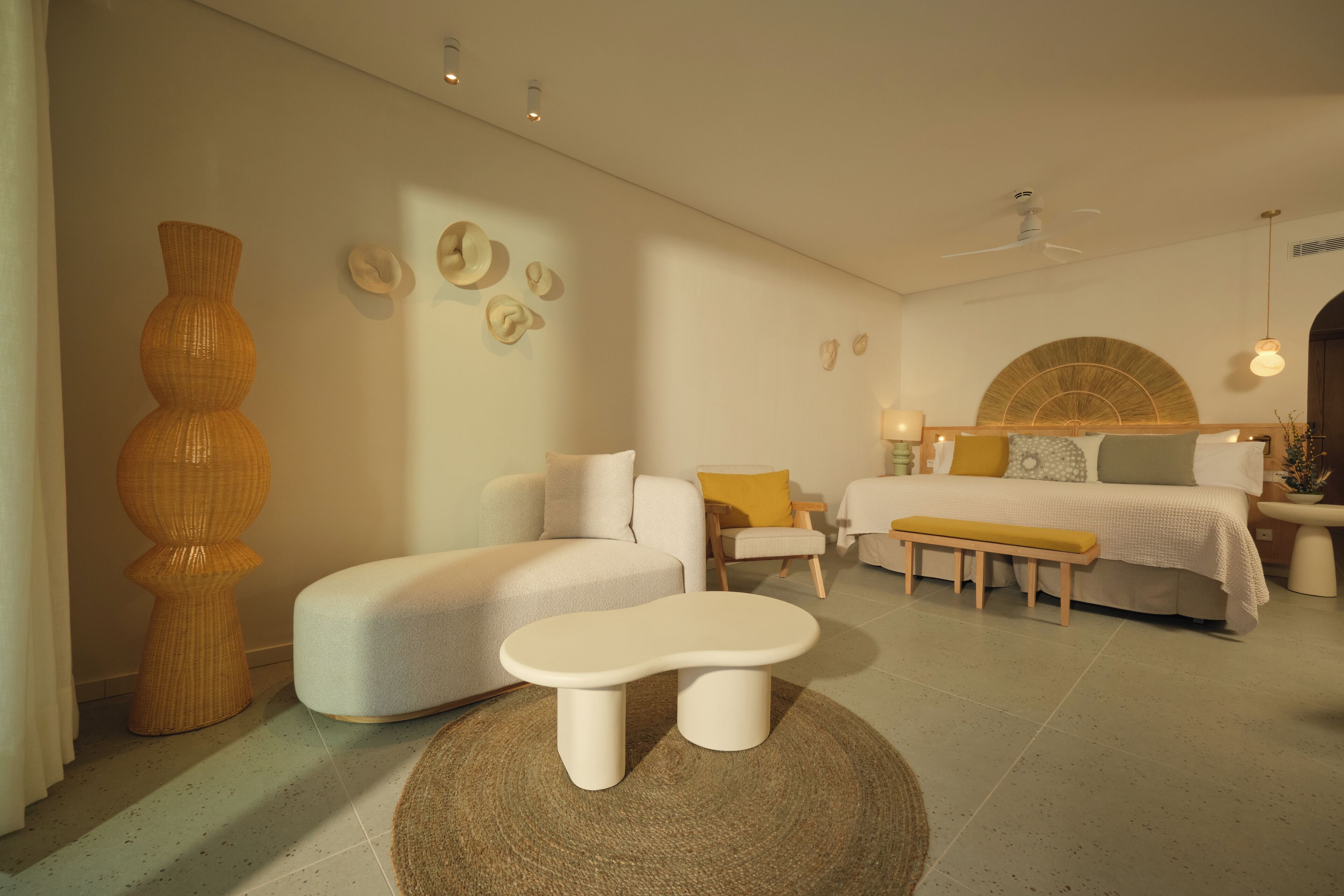 A modern bedroom with a sofa, a bench, a bed with a headboard, and a large vase.