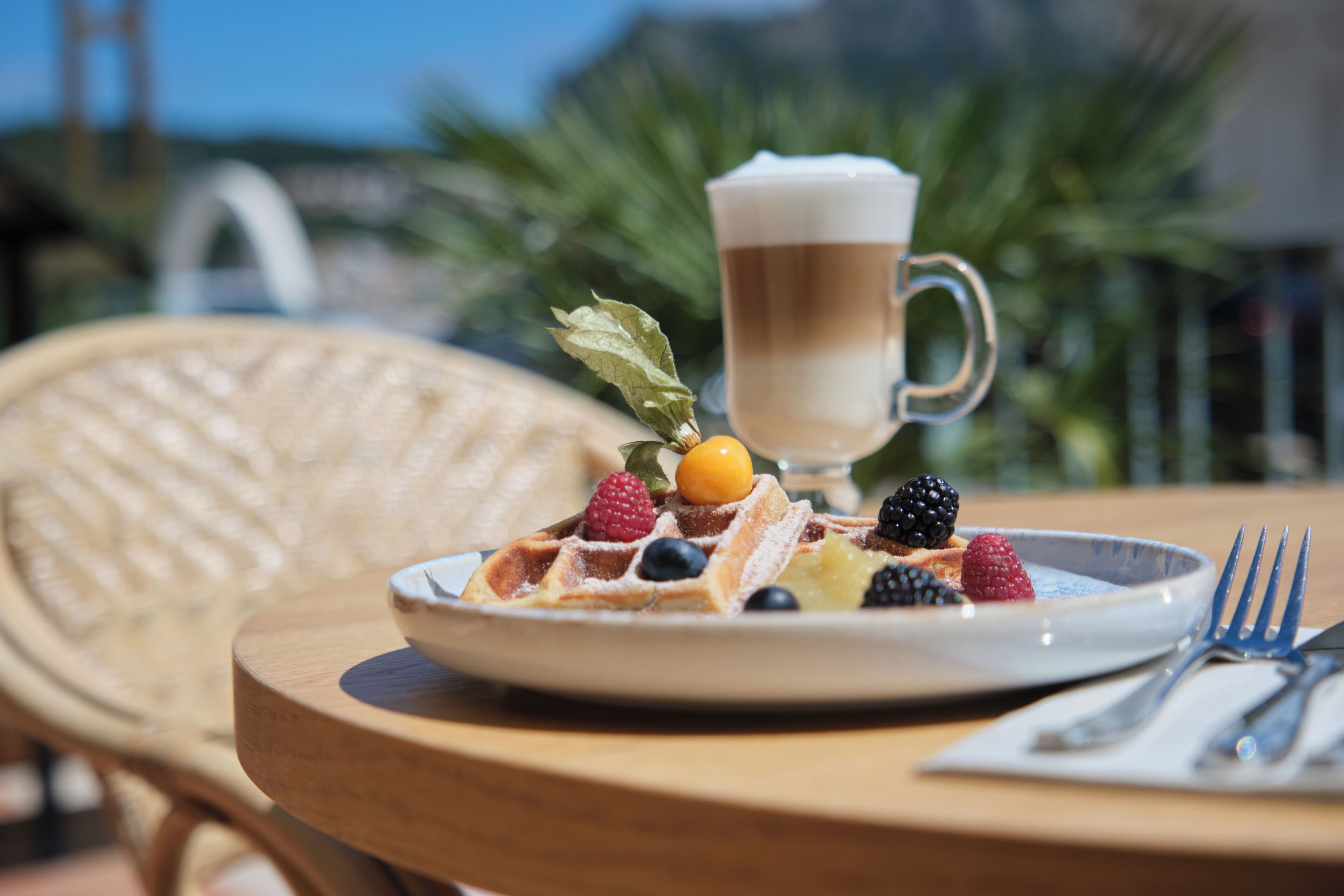 A breakfast setting with waffles topped with berries and a coffee mug.