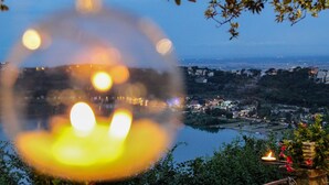 Nattebillede af et bybillede med en flod, oplyste bygninger og en dekorativ lampe i forgrunden.