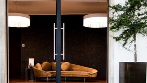 Et moderne interiør med en sofa, hængende lamper og en væg med mørkt mønster.