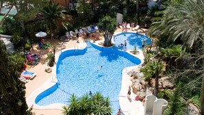 A large outdoor swimming pool with multiple lanes, surrounded by palm trees and lounge chairs. - Globales Nova (Calvia)