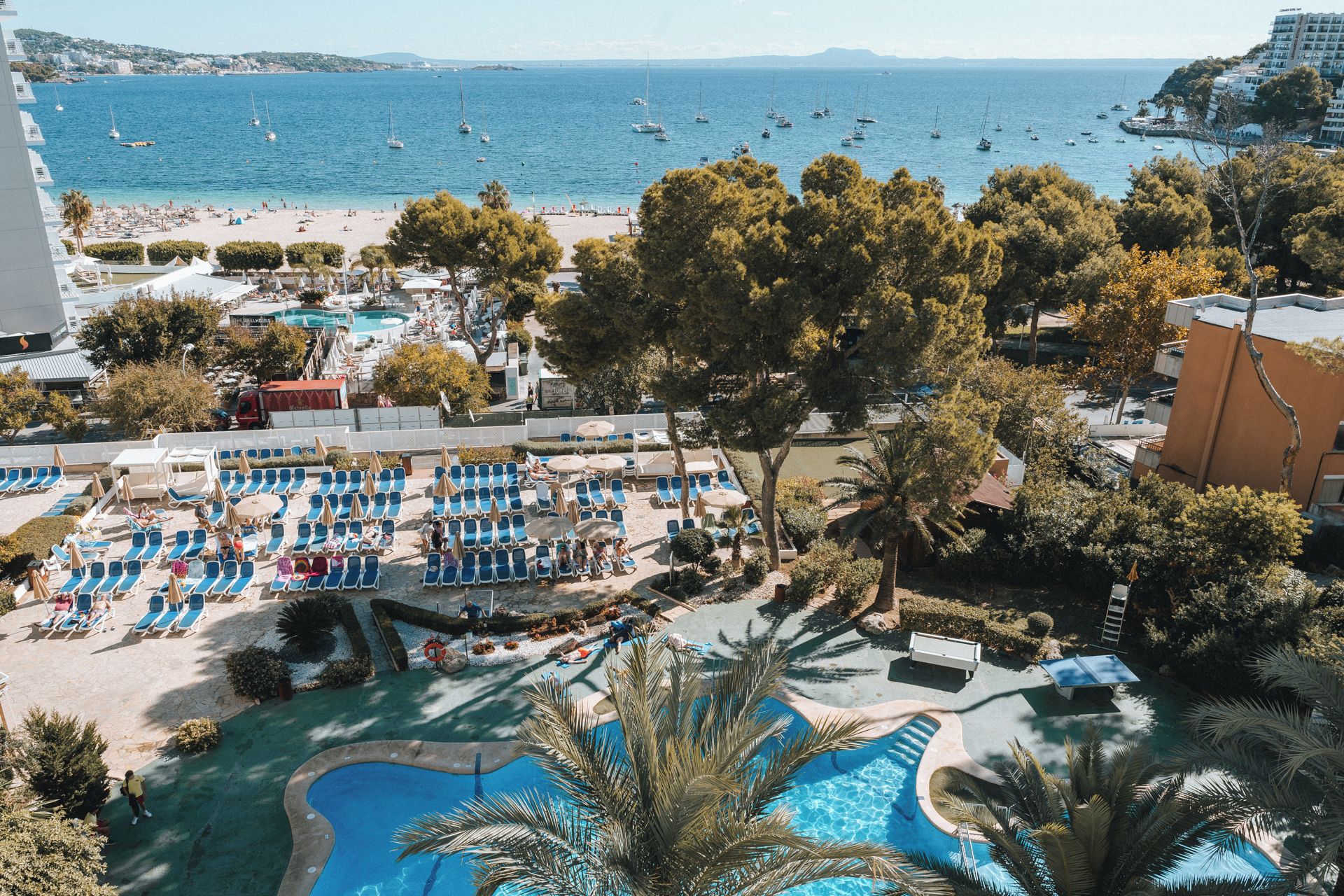 Un complex turístic amb diverses piscines, una platja i vista al mar.