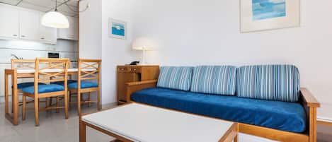 Un espacio habitable compacto con sofá, una mesa de comedor y una zona de cocina.