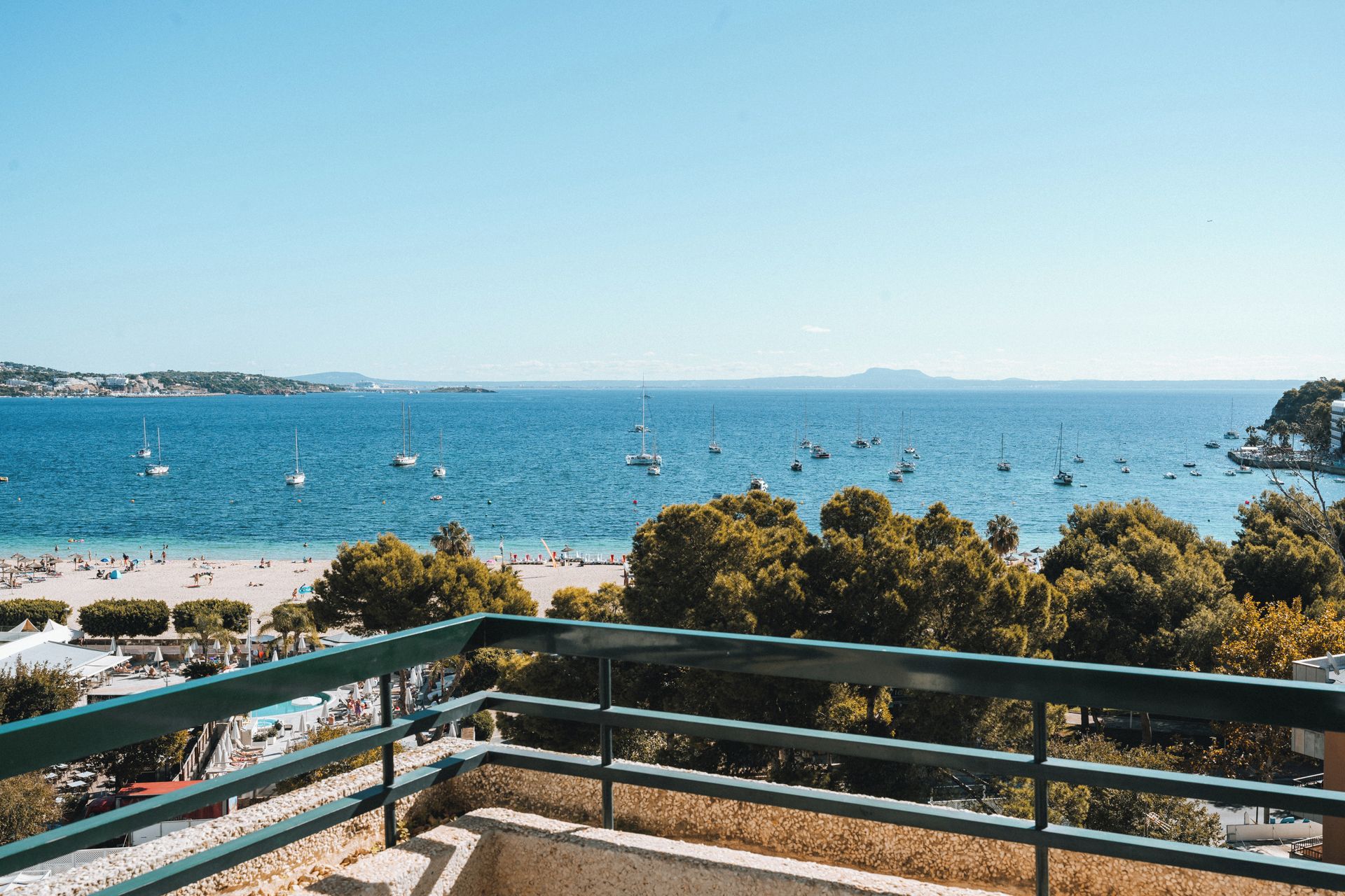 A coastal view with a beach, boats, and a clear sky.