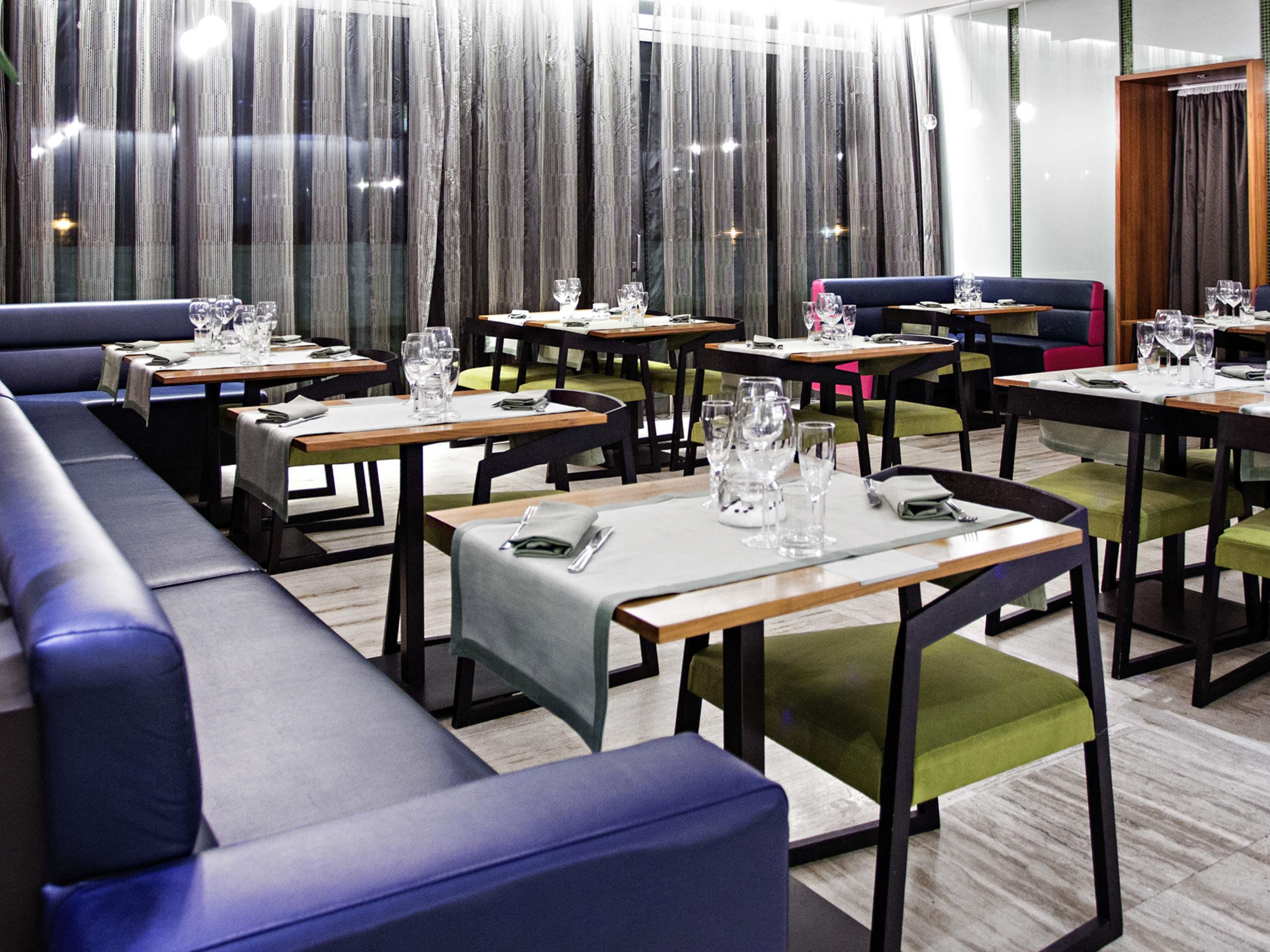 Un restaurante con varias mesas y cabinas, cada una dispuesta con cubiertos y vasos.