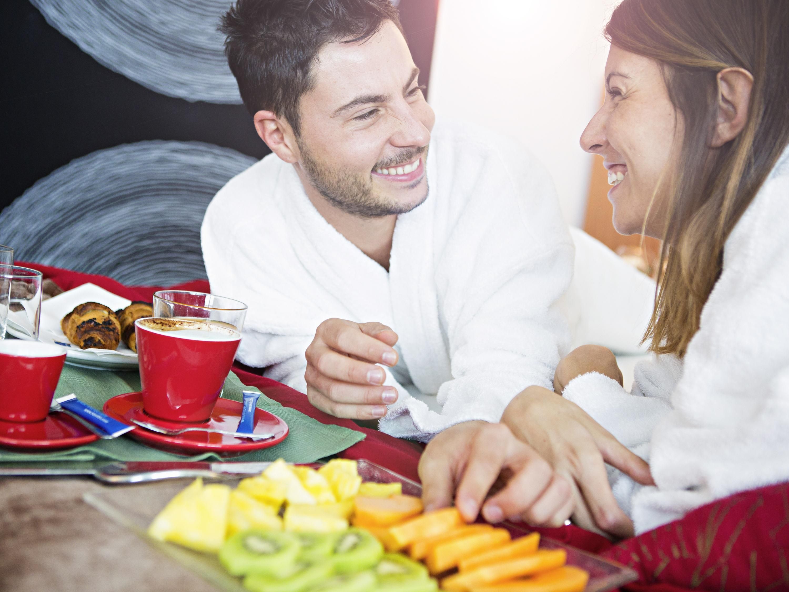 Un couple est assis à une table, devant des plats et des boissons.