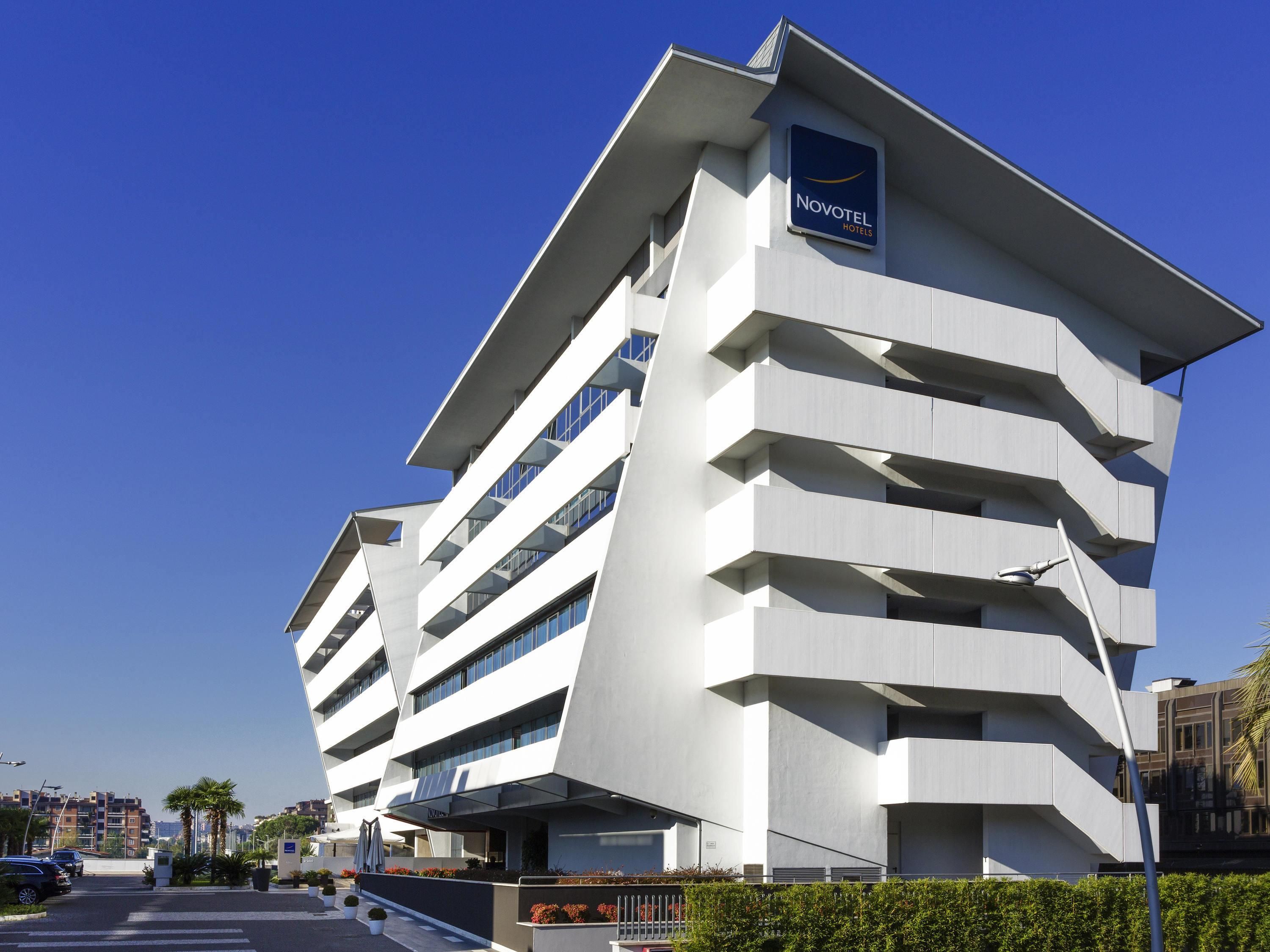 A modern hotel with a unique angular design, multiple balconies, and a clear sky.