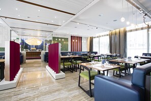 A modern restaurant with a central bar area, booths, and tables.