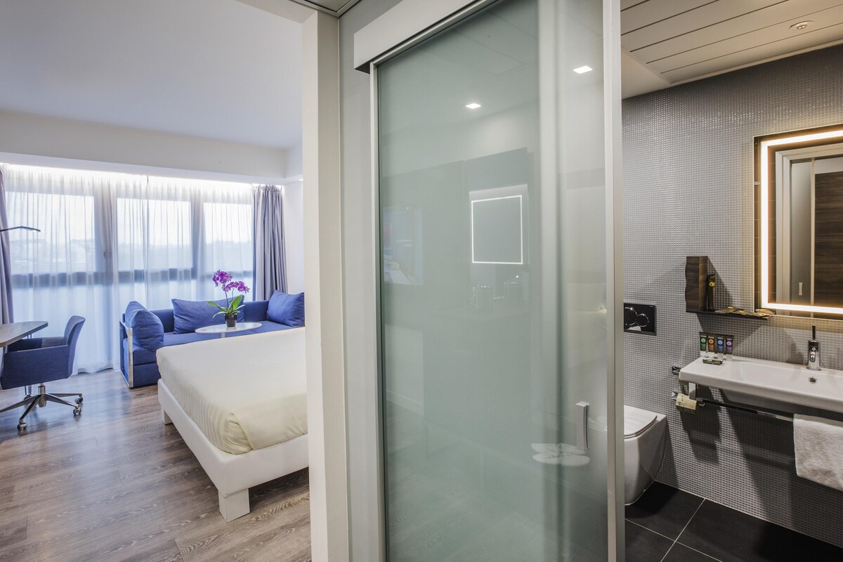 Una habitación de hotel moderna con una cama, un escritorio y un baño.