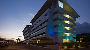 A modern hotel with a prominent sign, multiple floors, and a parking lot. - Novotel Roma Eur (Rome)