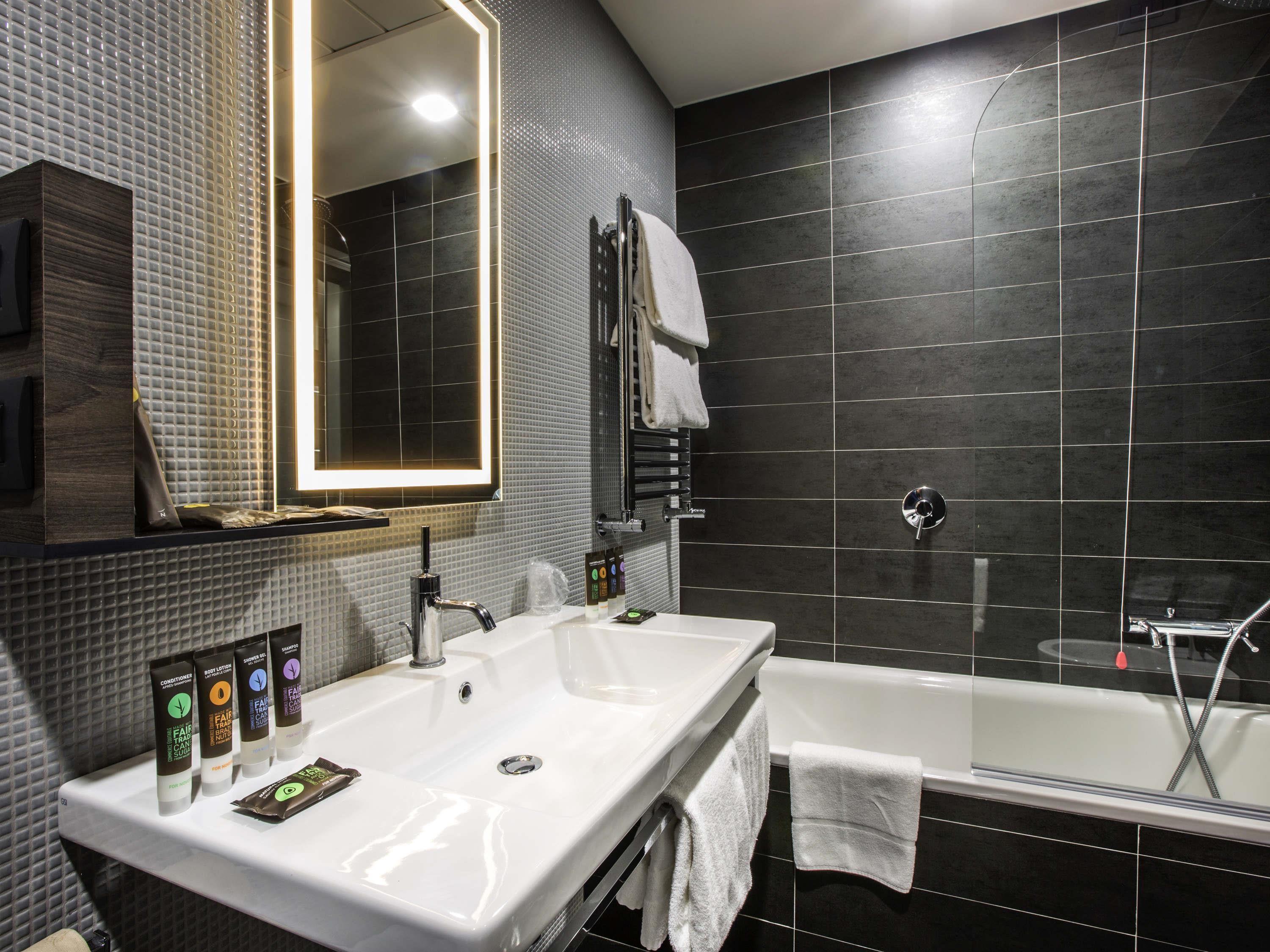 A modern bathroom with two sinks, a large mirror, a bathtub, and a shower.