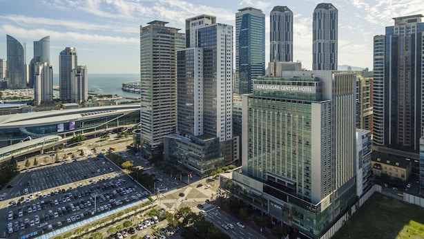 A modern hotel with a glass facade, located in a high-rise urban area with other tall buildings nearby. - Haeundae Centum Hotel (Busan)