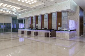 A modern hotel reception area with a marble counter, multiple service points, and a clean, polished floor. - Haeundae Centum Hotel (Busan)