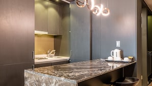 A modern kitchen with dark wood cabinets, a marble countertop, and a unique circular light fixture. - Haeundae Centum Hotel (Busan)