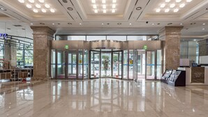 A hotel lobby with a revolving door, marble flooring, and a reception desk. - Haeundae Centum Hotel (Busan)