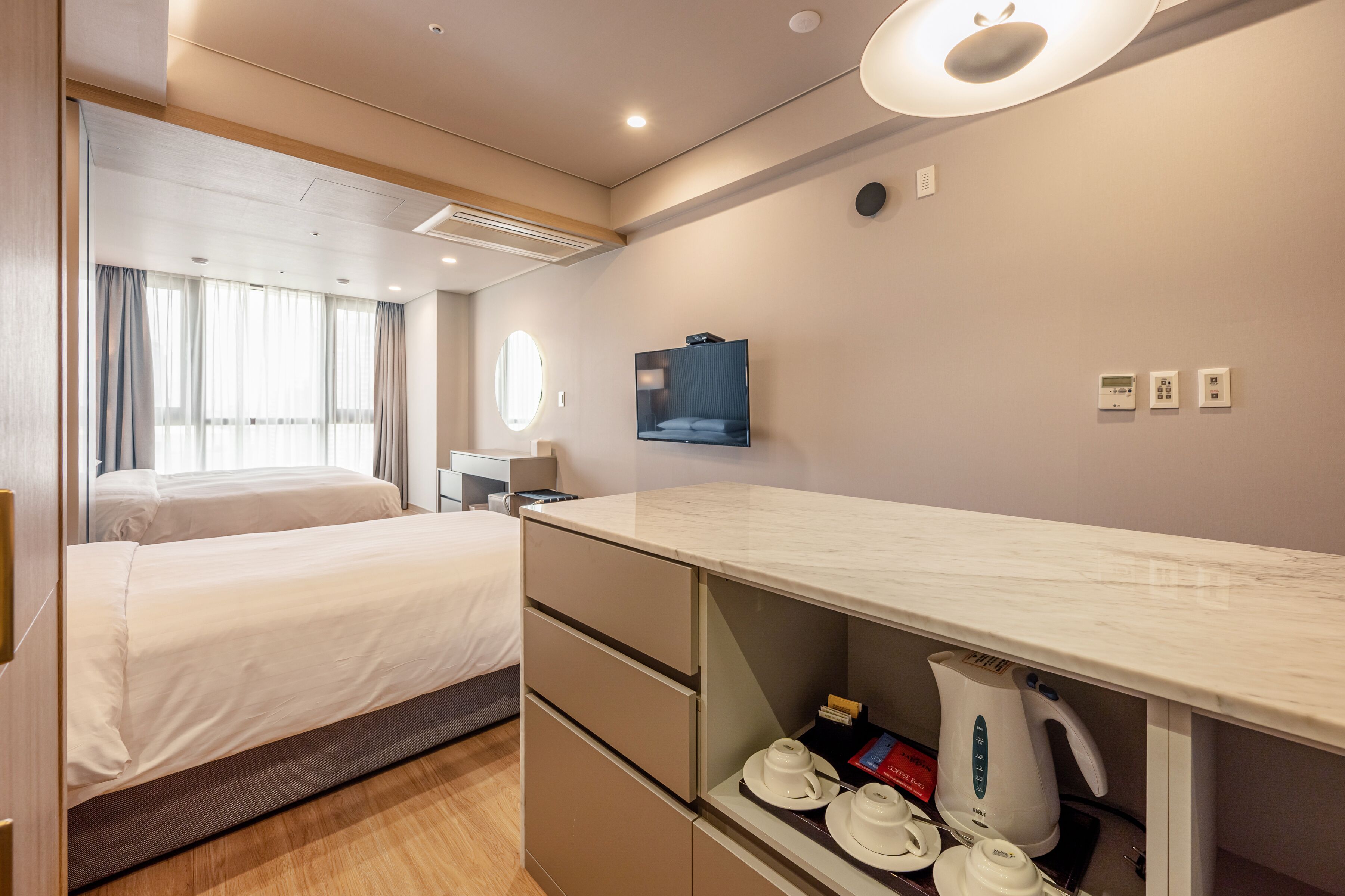A hotel room with two beds, a flat-screen TV, a minibar, and a coffee maker.