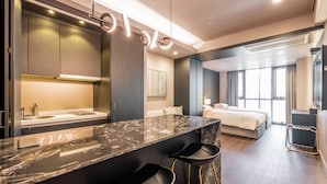 A modern hotel room with a marble kitchen island, a bed, and a large window. - Haeundae Centum Hotel (Busan)