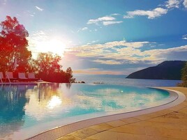 Una piscina al aire libre, sombrillas, sillones reclinables de piscina