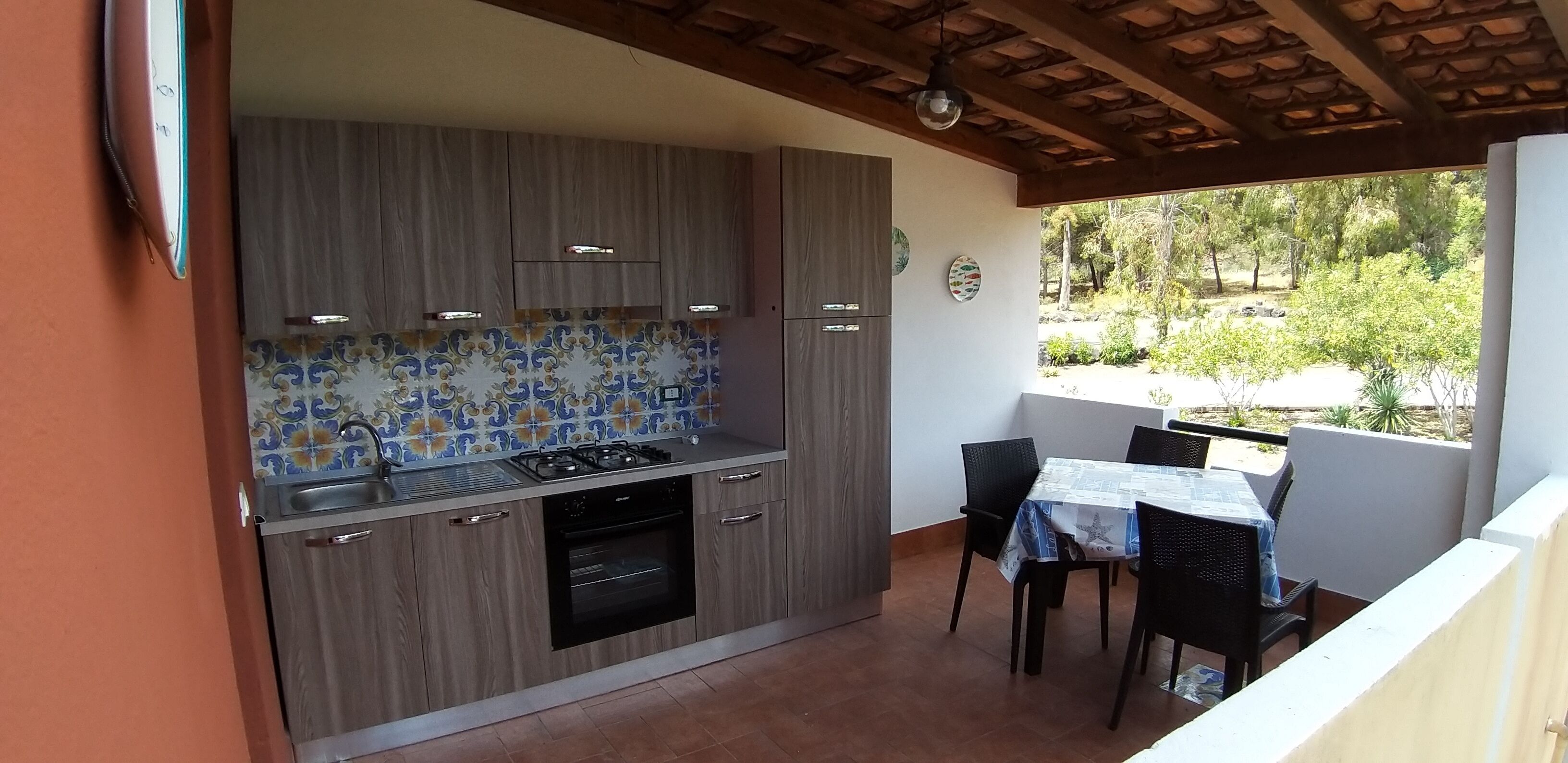 A kitchen with wooden cabinets, a gas stove, and a tiled backsplash. There is a dining area with a table and chairs.