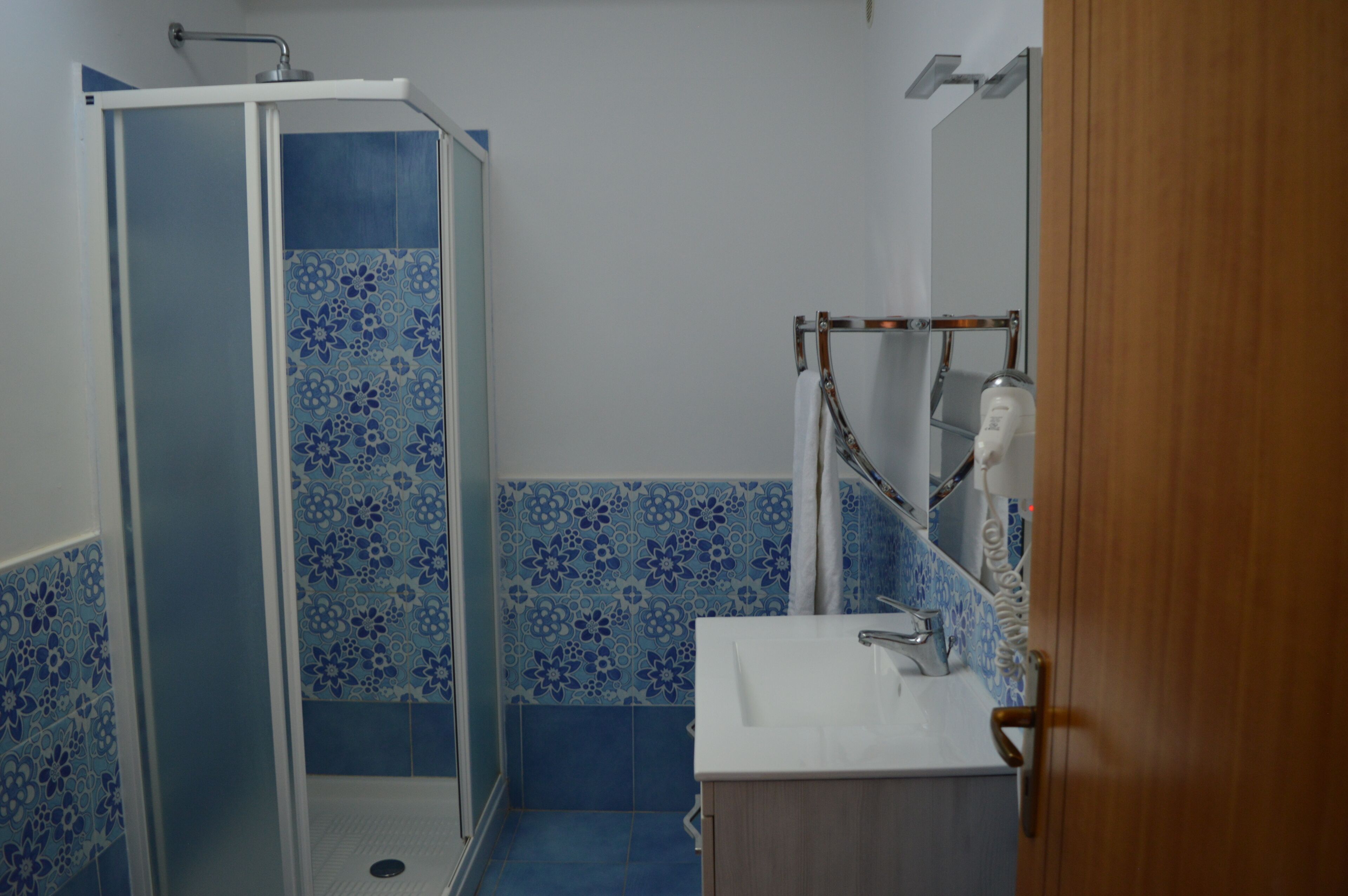 A bathroom with a shower enclosure, a sink, and a mirror.