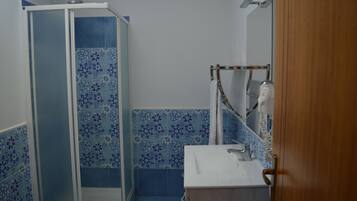A bathroom with a shower enclosure, a sink, and a mirror.