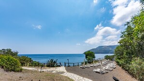 Una zona junto a la playa con un camino de piedra que conduce a sillas de descanso al borde del agua.