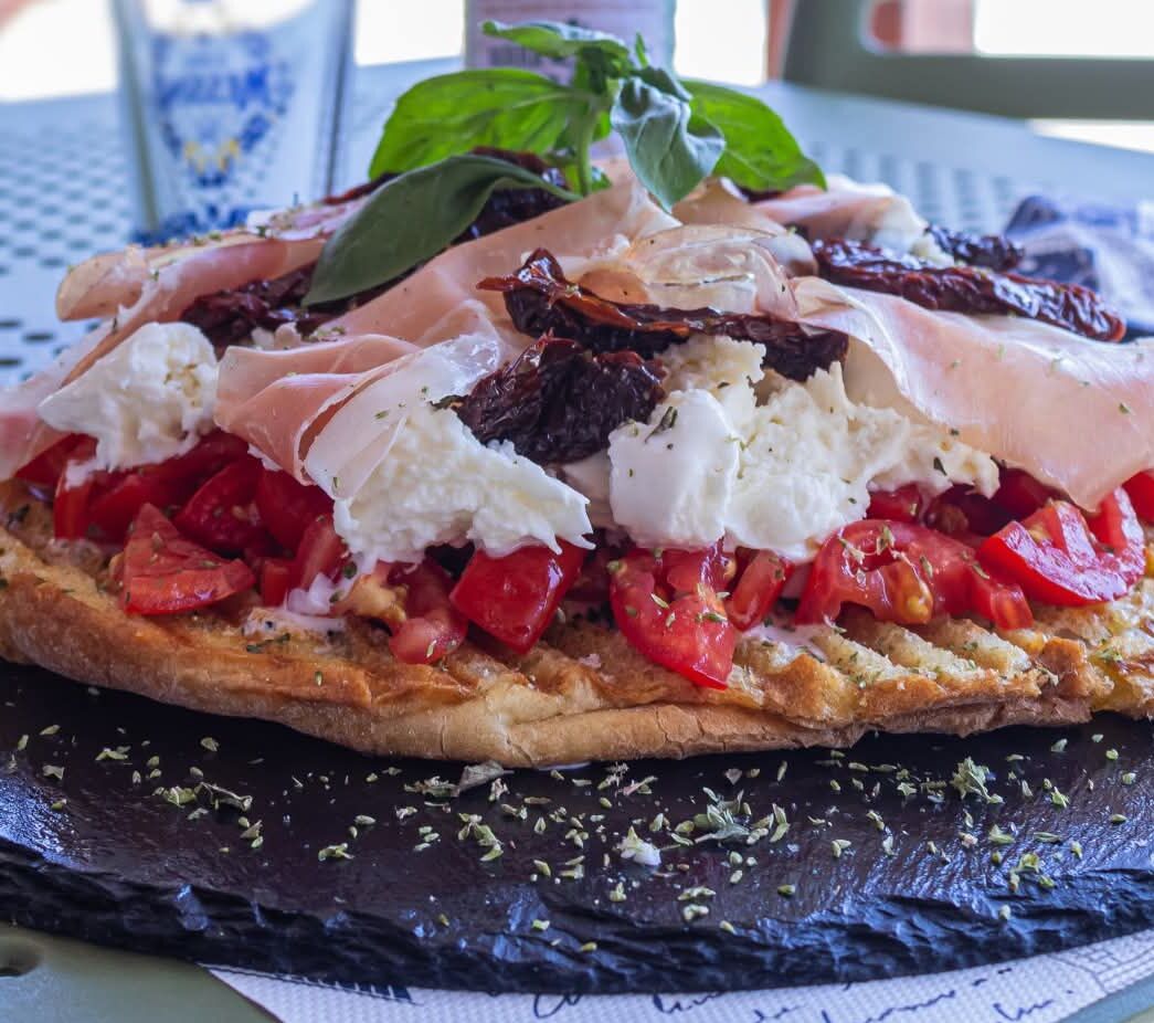 A pizza with various toppings on a black slate plate.
