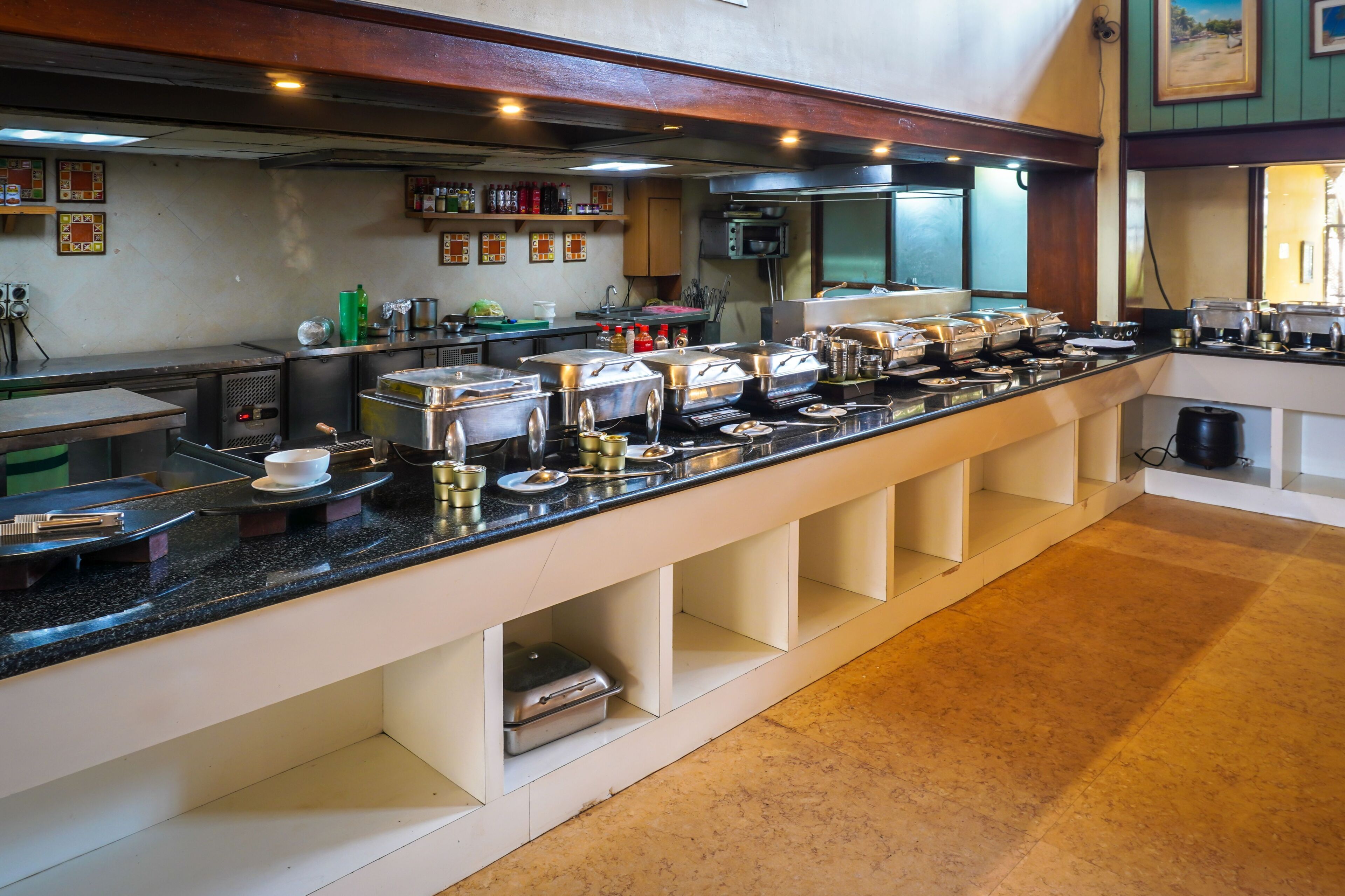 Montaje de bufé con varias estaciones de servicio, una variedad de recipientes de comida y una zona de cocina al fondo.