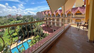 A balcony with a pool, surrounded by greenery and buildings with red roofs.
