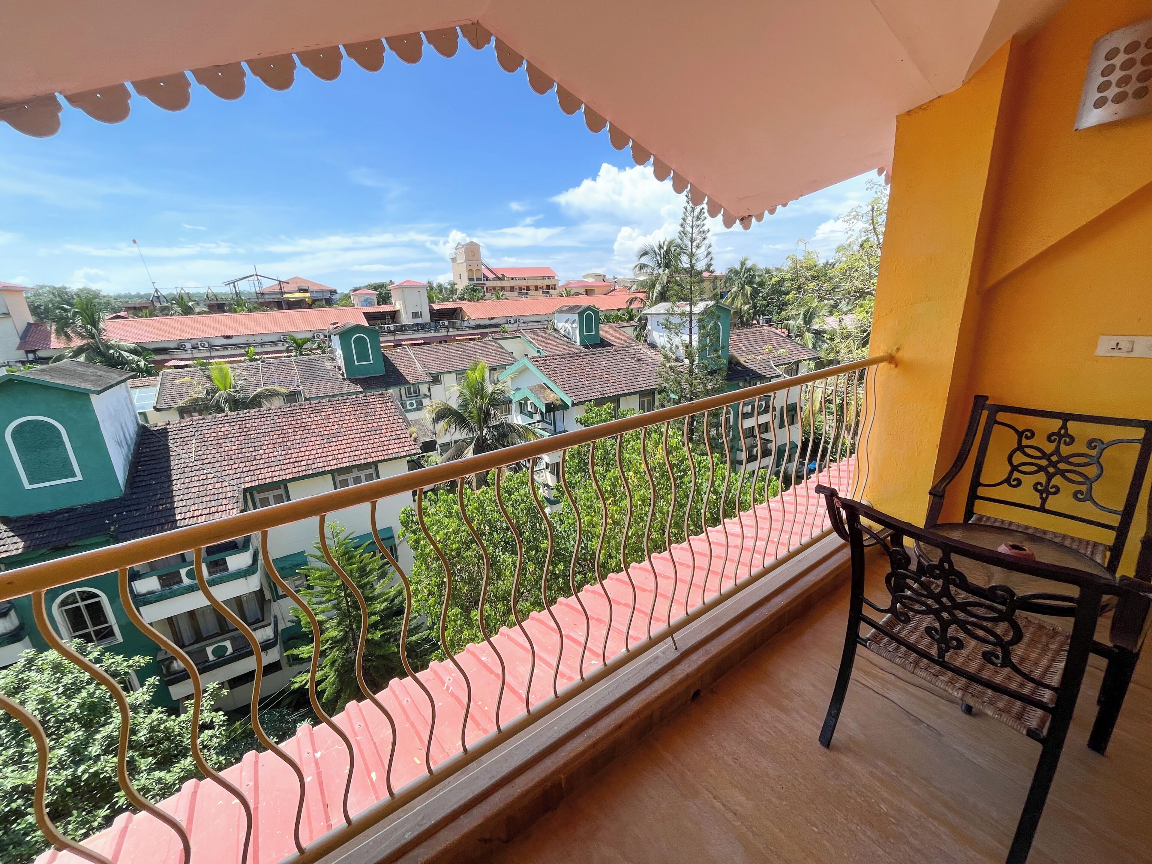 Un balcon donnant sur un quartier résidentiel, avec une chaise et une rambarde.