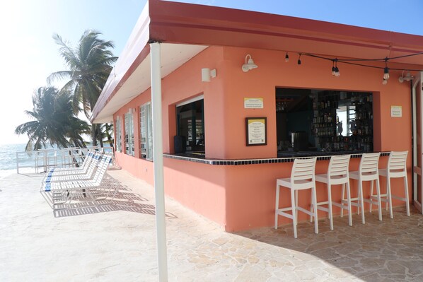 A beachside bar with a red exterior, outdoor seating, and a view of the ocean. - Parador MaunaCaribe (Maunabo)