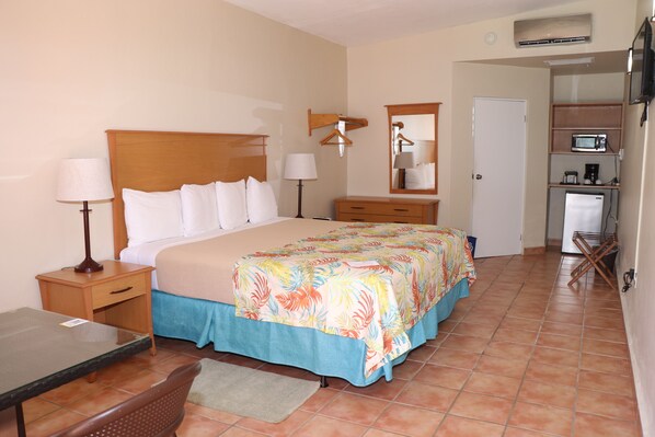A hotel room with a bed, bedside tables, a desk, a chair, a microwave, and a refrigerator. - Parador MaunaCaribe (Maunabo)