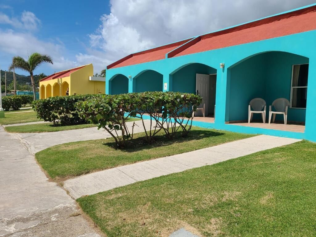 Un hotel con varias edificaciones conectadas, cada una de un color diferente. Senderos y un césped bien cuidado al frente.