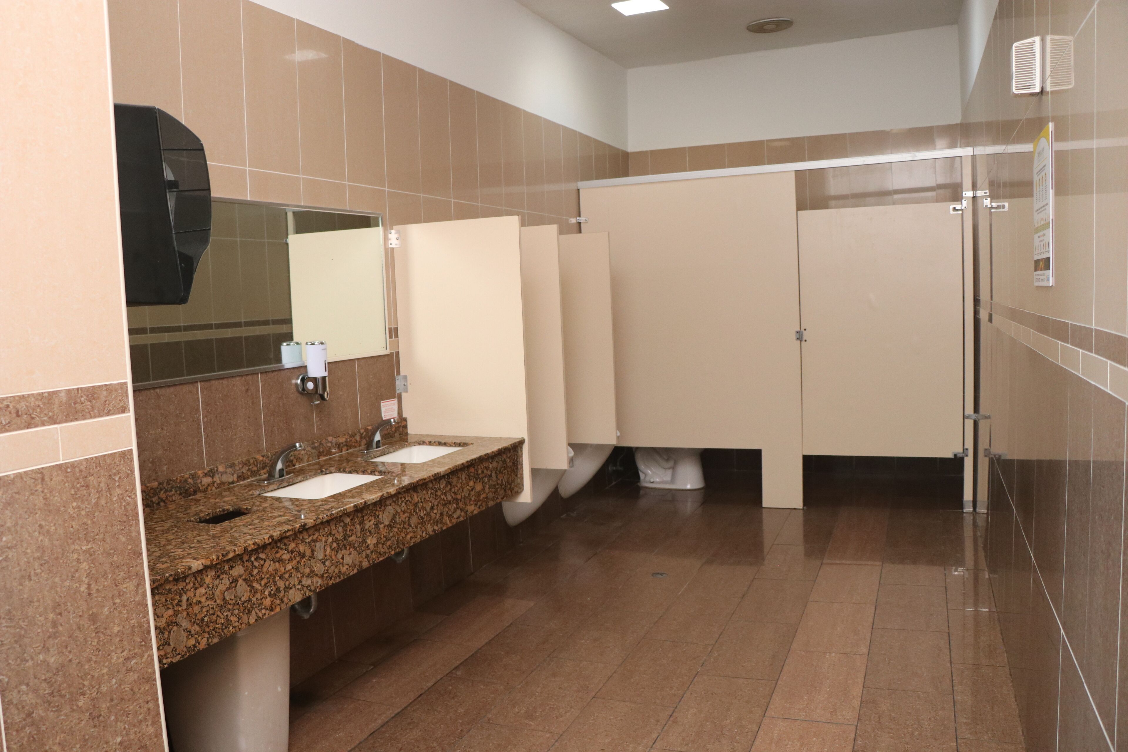 A public restroom with granite countertops, sinks, a mirror, and a tiled floor.
