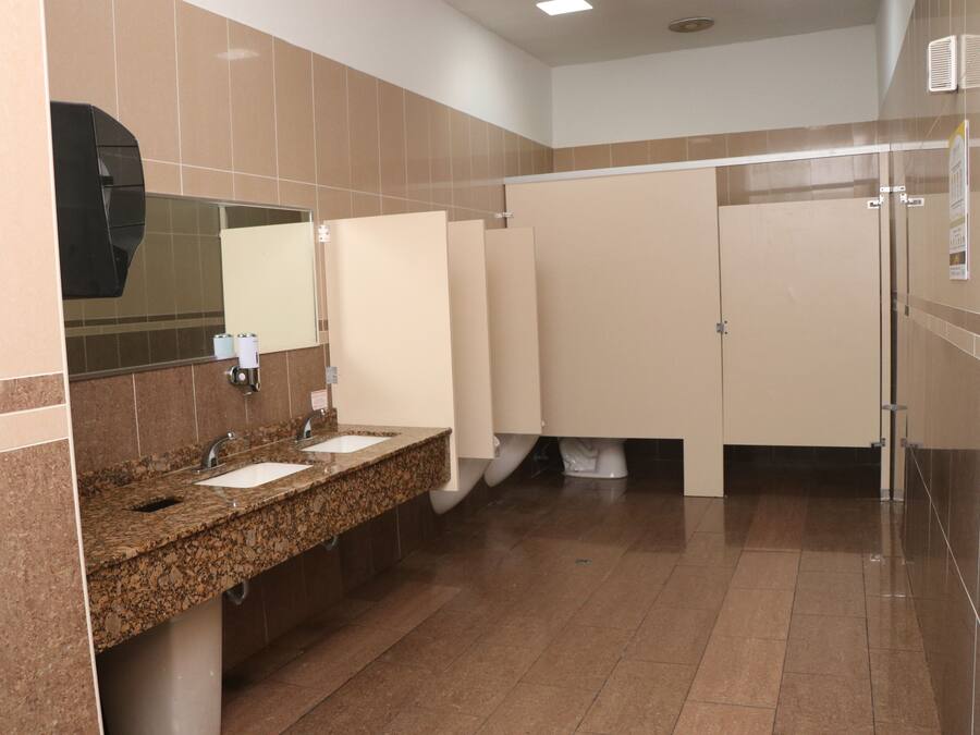 A public restroom with granite countertops, sinks, a mirror, and a tiled floor.