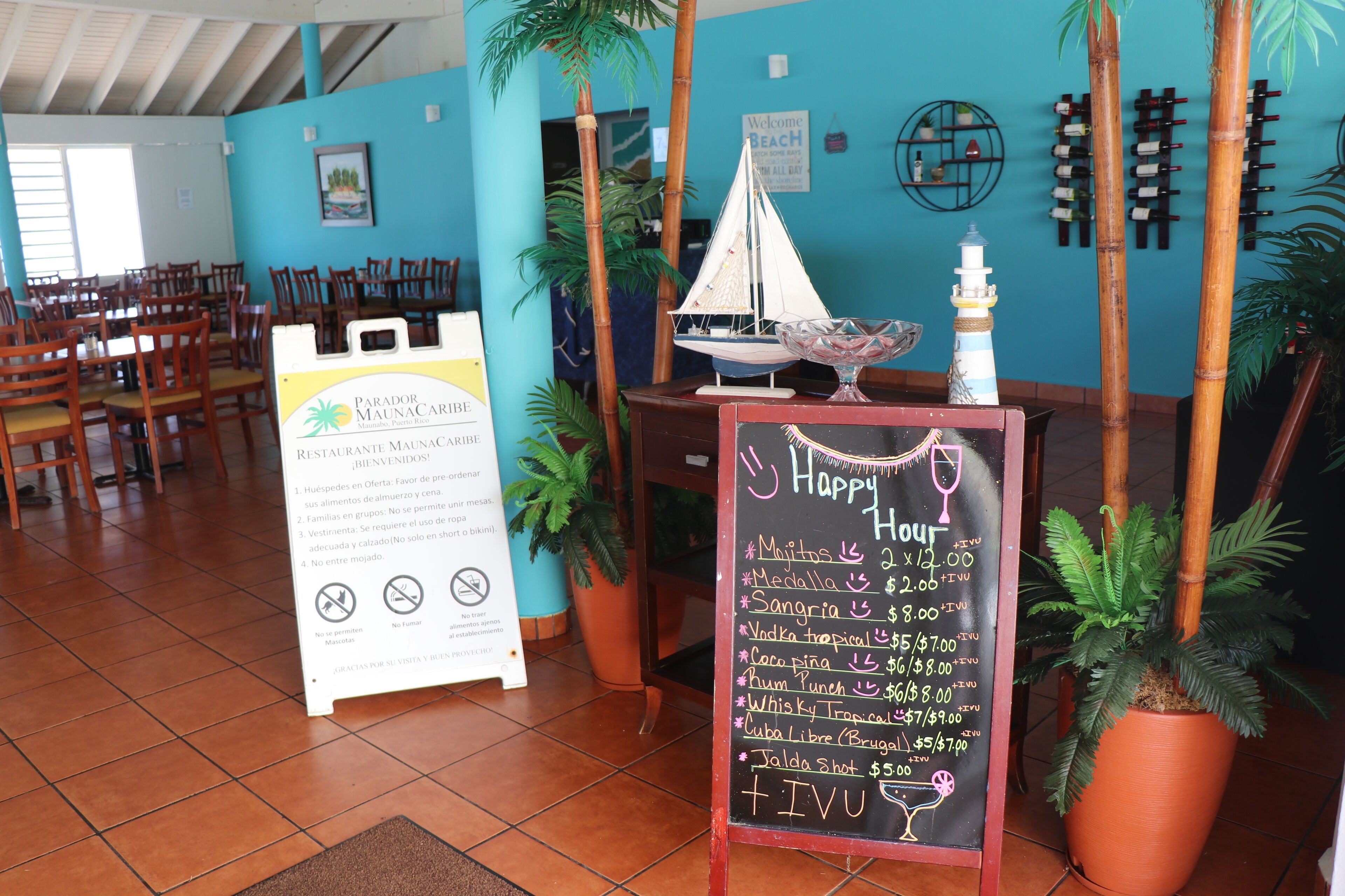 A restaurant interior with wooden chairs, a sailboat model, and a chalkboard menu.