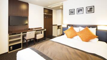 A hotel room with a bed, a desk, a chair, a TV, and a wardrobe.