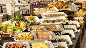 Un bufé con diversos alimentos, incluyendo ensaladas, carnes y productos de panadería.
