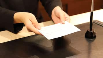 A person holding a card at a counter with a black surface and a black object on it.