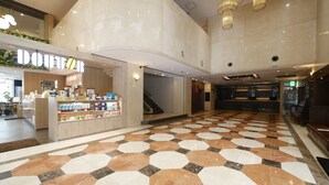 A spacious lobby with a check-in counter, a staircase, and a patterned floor.