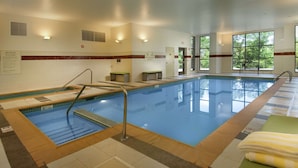 An indoor swimming pool with clear lanes, a lifeguard chair, and a bench. - DoubleTree by Hilton Sterling - Dulles Airport (Sterling)